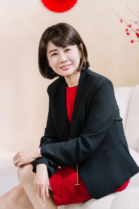 側身坐在暖調居家沙發上，雙手輕放膝頭流露柔和放鬆的神態