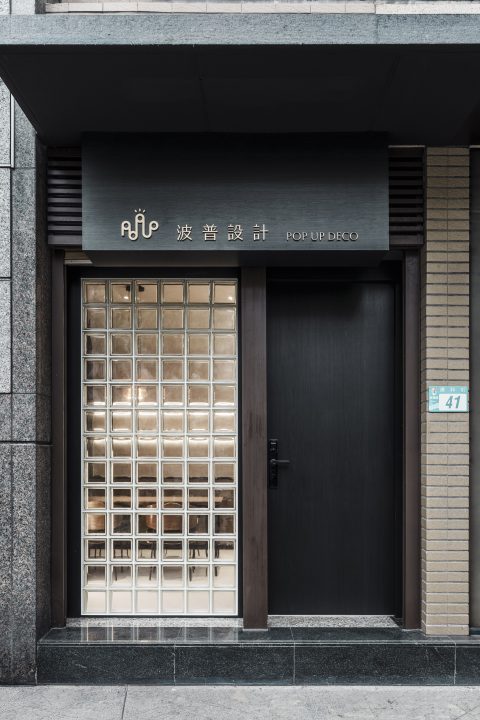 玄關外觀設有黑色大門與招牌，旁側為透光玻璃磚立面