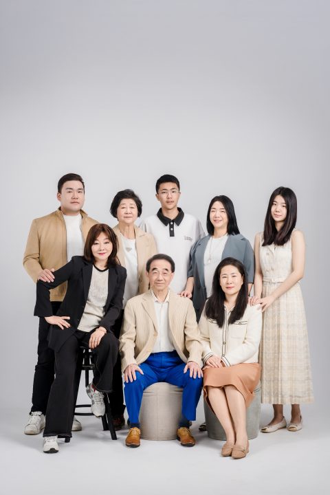 祖父母與兒女孫輩齊聚，身穿卡其西裝與米白洋裝在棚內端正合影