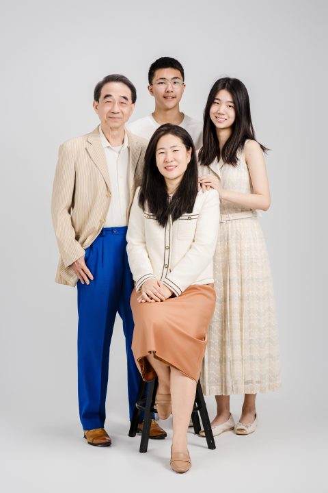 母親端坐於高腳椅中央，父親與一雙兒女圍繞身旁面向鏡頭微笑