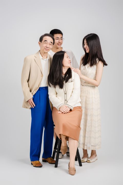 坐在椅上的母親轉頭望向女兒，母女倆搭著肩膀相視開懷微笑