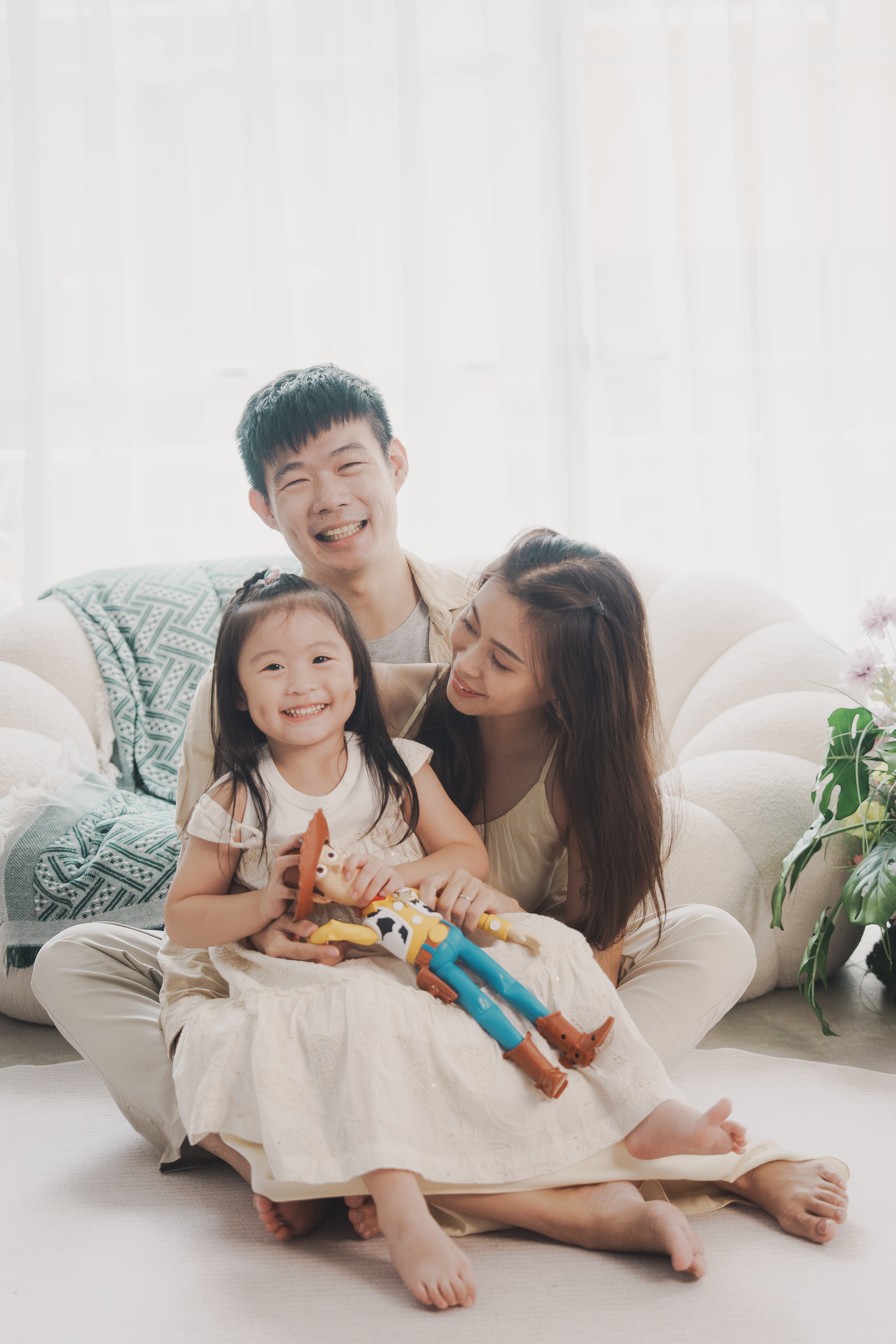 懷抱胡迪玩偶的女童坐在地毯上，媽媽溫柔貼靠在旁